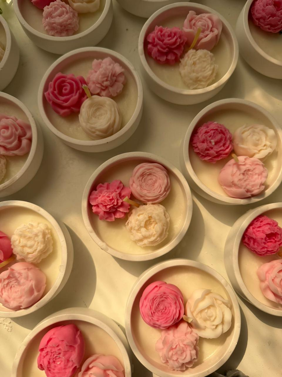 Round candle favor topped with three small pink and ivory wax flowers