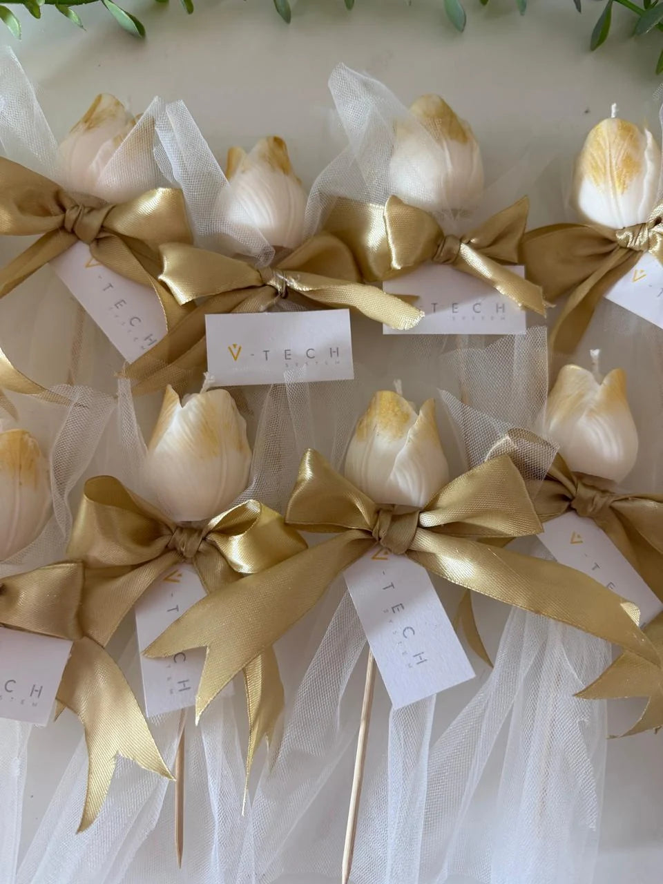 Ivory tulip candle favor with gold-painted tips, white tulle, and champagne satin bow