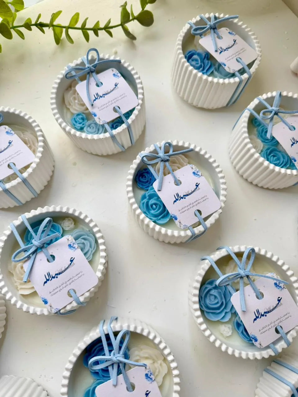 White ribbed bowl candle with blue and ivory wax roses and a personalized tag