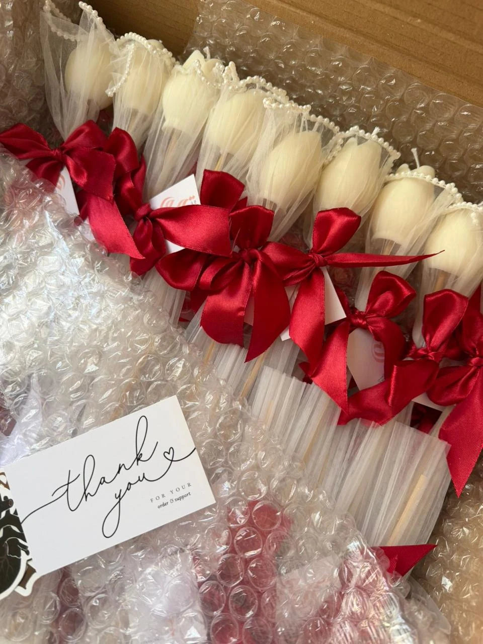 Ivory tulip candle favor in pearl-trimmed tulle with a deep red satin bow