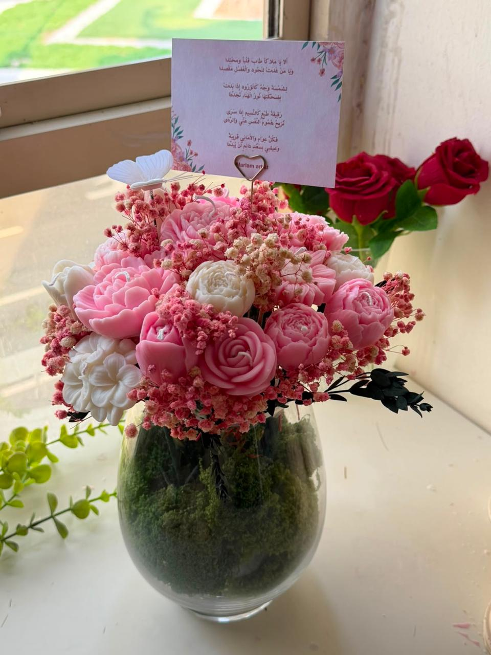 Pink and ivory wax flower bouquet in a glass moss vase